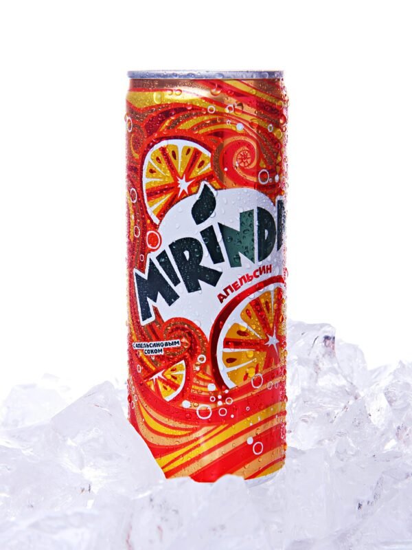 Vibrant Mirinda soda can in close-up, chilled on ice for a refreshing look.